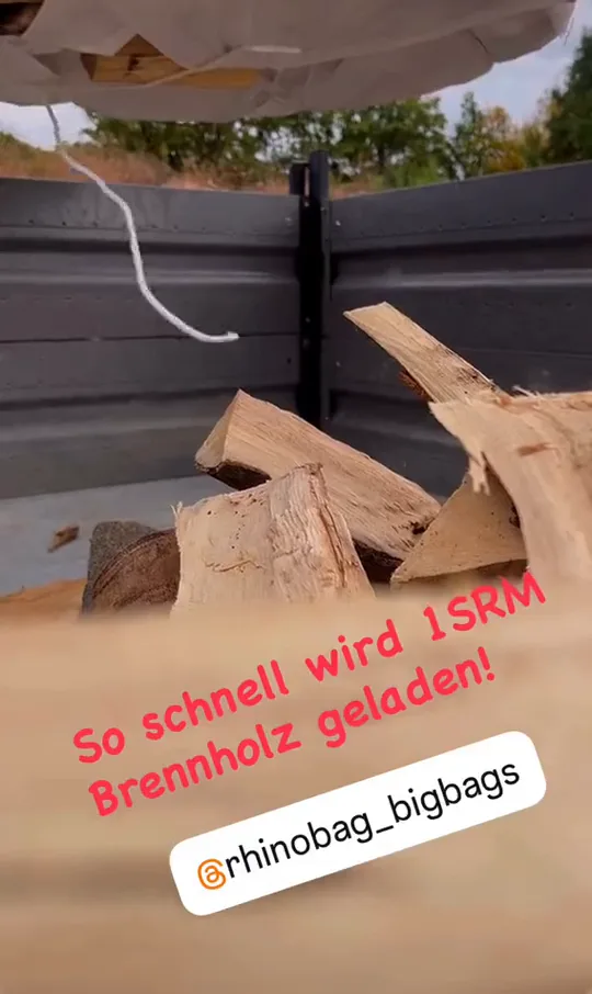Video: Ein Bag wird &uuml;ber dem Anh&auml;nger entleert, das Brennholz f&auml;llt auf die Ladefl&auml;che